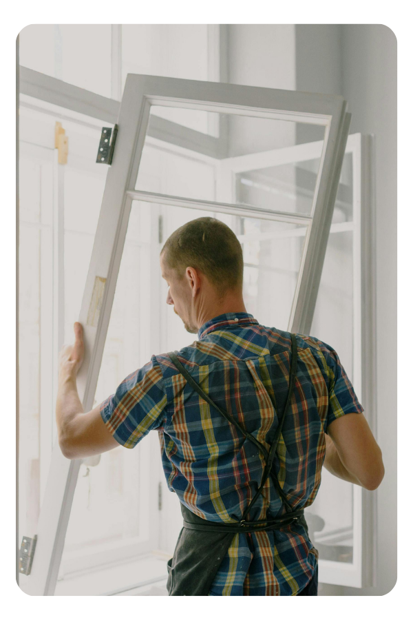 A man fitting a window in a property