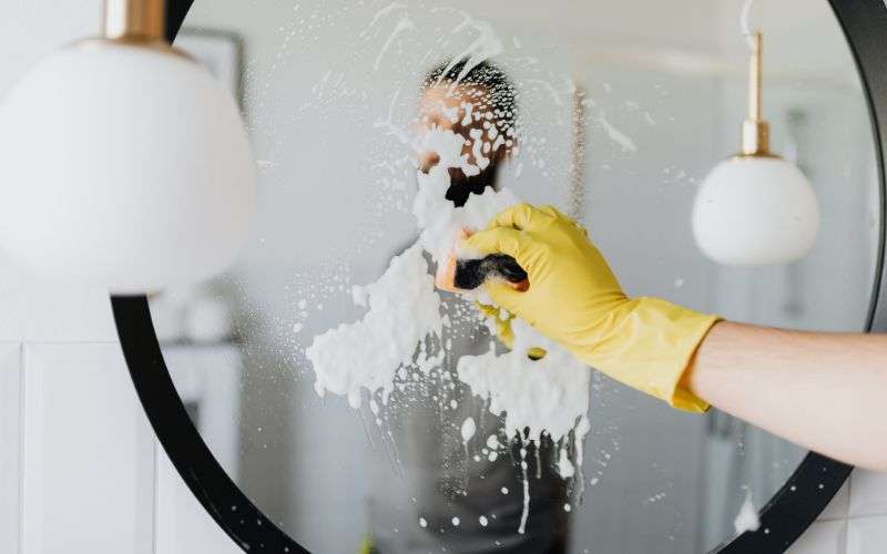 A cleaner cleaning a mirror
